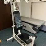White and black exercise machine with leg press and chest press stations in a clinic setting